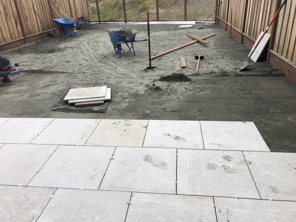 A patio is being constructed with concrete tiles.
